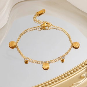 Gold double-layer bracelet with shell charms and zircon accents on a mirror