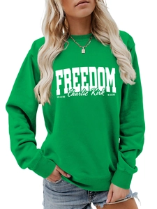 Detail of the green crewneck sweatshirt showing white Freedom and Charlie Kirk text print
