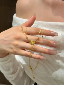 Detailed view of a gold rose pendant with layered chain and beads on a neck