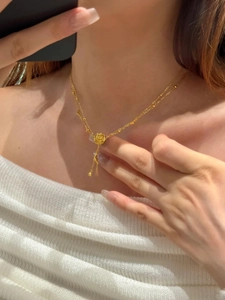 Detailed view of a gold-plated rose flower pendant with tassel chains on a model