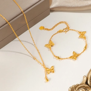 Parure collier et bracelet papillon doré avec texture mate sur surface élégante