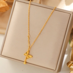 Collier papillon doré avec pendentif pompon et chaîne à maillons sur boîte à bijoux