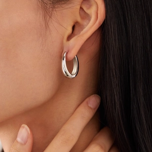 Minimalist silver U-shaped horseshoe earrings shown on model with polished metallic finish