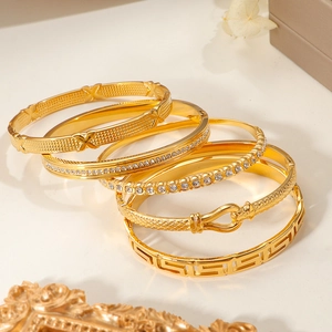 Set de cinco brazaletes de acero de titanio dorado con pavé de diamantes y grecas