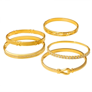 Set de cinco brazaletes de acero de titanio dorado con greca clásica y cristales finos