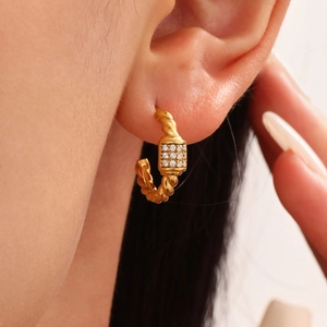 Golden twisted rope C-hoop earrings with sparkling cubic zirconia baguette on earlobe