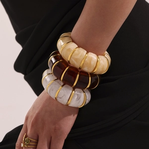 Three-piece set of wide resin bangles in marble and amber colors with gold metal accents
