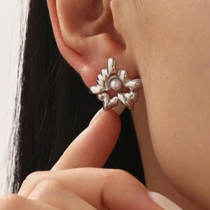 Irregular liquid metal silver earrings with a white pearl on a model's ear