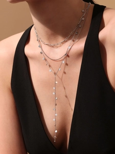 Detailed view of layered silver necklace featuring sequins and a long Y-shaped tassel drop