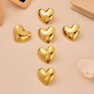 Polished heart-shaped stainless steel stud earrings in golden finish on a soft background