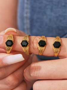 Close-up of vintage gold rings with hexagonal black stones and floral relief engraving