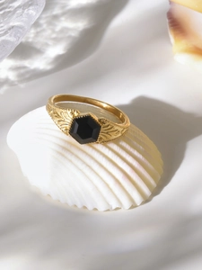 Detailed view of gold vintage ring with black hexagonal stone and floral carvings