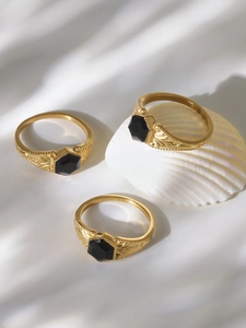Detailed view of vintage gold rings with black hexagonal stones and leaf engravings