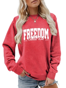 Detail of red crewneck sweatshirt featuring white FREEDOM text and signature print