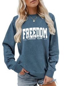 Detail of the white 'FREEDOM Charlie Kirk' print on a blue-grey crewneck sweatshirt