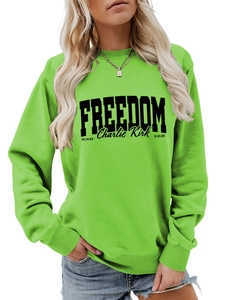 Detail of the bright green sweatshirt featuring bold black FREEDOM text and branding