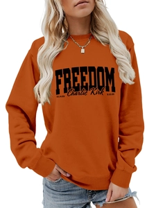 Detail of orange crewneck sweatshirt featuring black FREEDOM text and Charlie Kirk signature