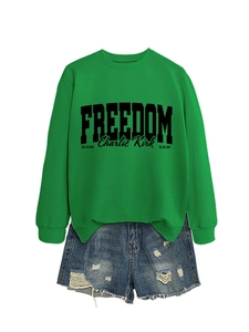 Detail of green Freedom Charlie Kirk sweatshirt paired with distressed denim shorts