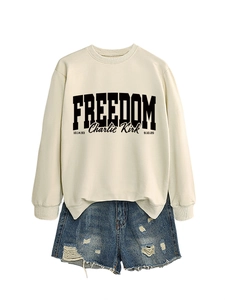 Detail of beige sweatshirt with Freedom print paired with distressed denim shorts