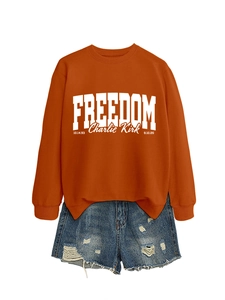 Close-up of orange sweatshirt with white FREEDOM letters and ripped denim shorts
