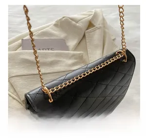 Detail view of black quilted PU leather handbag with elegant gold metal chain links