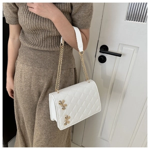 Detail showing white quilted texture and golden butterfly accents on the elegant bag
