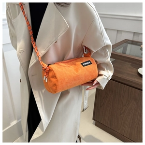Detail view of bright orange corduroy cylinder bag with thick woven shoulder strap