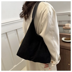 Close-up of black faux suede tote bag with smooth leather strap in minimalist interior