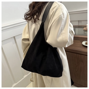 Retro black faux suede tote bag with leather strap worn by model in minimalist style