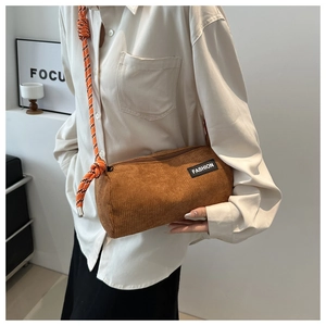 Close-up of brown corduroy barrel crossbody bag with decorative rope strap and fashion label