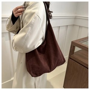 Model wearing a large dark brown faux suede tote bag with minimalist shoulder strap design
