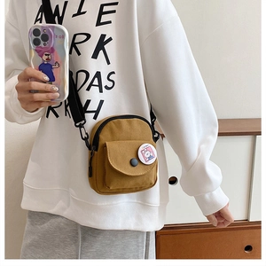 Close-up of brown canvas crossbody bag featuring a cute bunny badge and adjustable strap
