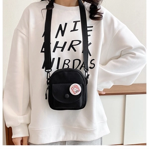 Black canvas mini crossbody bag detail with cute white bunny badge and adjustable strap