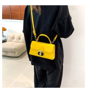 Dettaglio di una mini borsa gialla brillante con fibbia a forma di T nera e oro