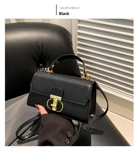 Dettaglio della borsa squadrata in pelle nera opaca con chiusura a T dorata e tracolla