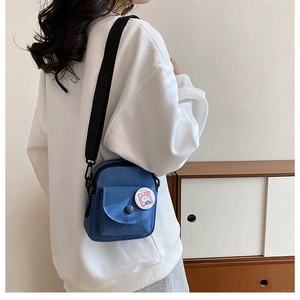 Blue canvas crossbody bag with adjustable black strap and cute rabbit badge detail
