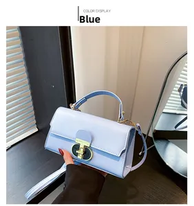 Dettaglio della borsa a mano quadrata in pelle azzurra con chiusura ad anello dorata e profilo