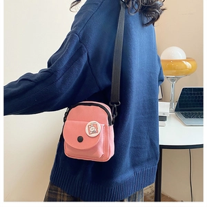 Pink canvas mini crossbody bag detail featuring cartoon bunny badge and adjustable strap