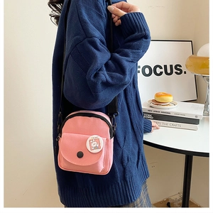 Close-up of pink mini canvas shoulder bag with cartoon rabbit badge and adjustable strap