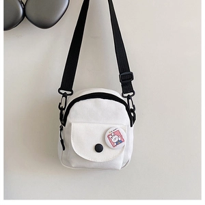 Detail of white canvas crossbody bag featuring adjustable black strap and cute rabbit badge