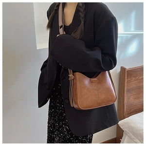 Detail of brown vintage PU leather bag featuring a wide patterned woven shoulder strap