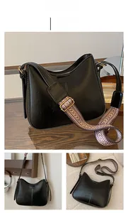 Detail view of black vintage hobo bag with colorful wide woven jacquard shoulder strap