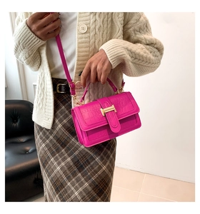 Dettaglio borsa fucsia con trama a coccodrillo e fibbia H dorata su maglione beige