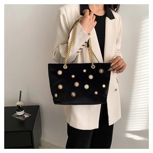 Sac fourre-tout tendance en velours noir avec rivets dorés et bandoulière sur le modèle