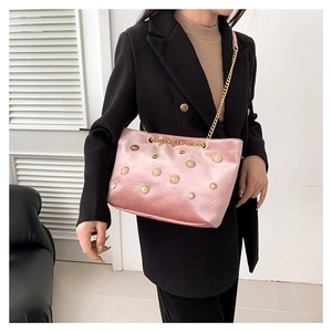 Sac à bandoulière en velours rose avec rivets soleil dorés porté par un mannequin