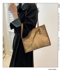 Detail of vintage brown suede tote bag featuring slim leather straps and gold metal rivets
