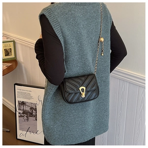 Détail du sac en cuir matelassé noir avec motif en V doré, chaîne et accents métalliques