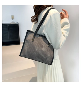 Detail view of grey frosted tote bag featuring gold rivets and slim black shoulder straps