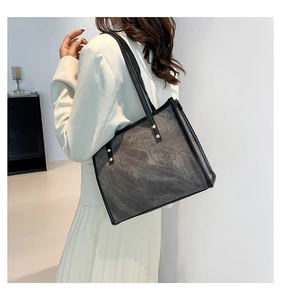 Detail of vintage tote bag featuring grey matte texture with black leather trim and studs