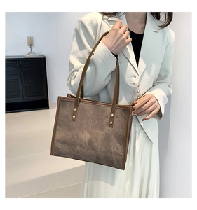Detail of vintage tote bag featuring brown leather handles and golden rivets